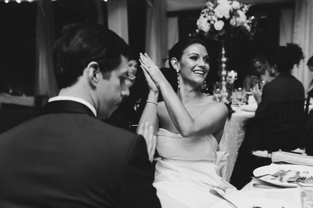 A photojournalistic photograph of a bride clapping during the wedding speeches at the Castle Hill Inn in Newport, Rhode Island