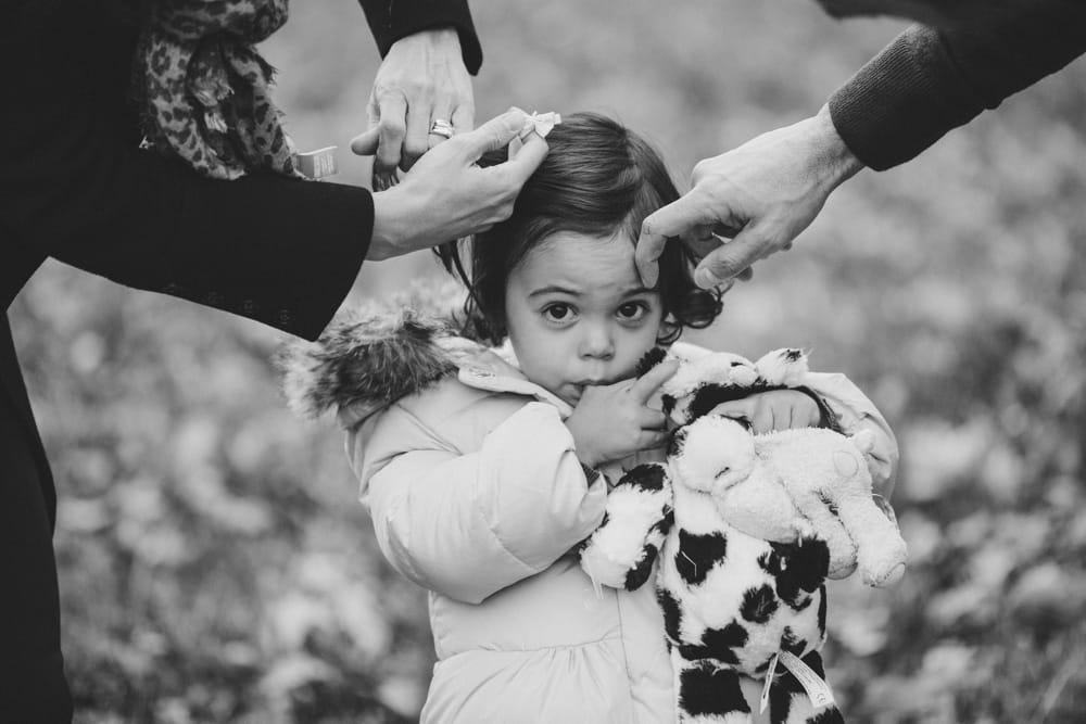 A funny and cute documentary photograph of a little girl getting her hair fixed before her lifestyle family photo session at the Arnold Arboretum in Boston, Massachusetts