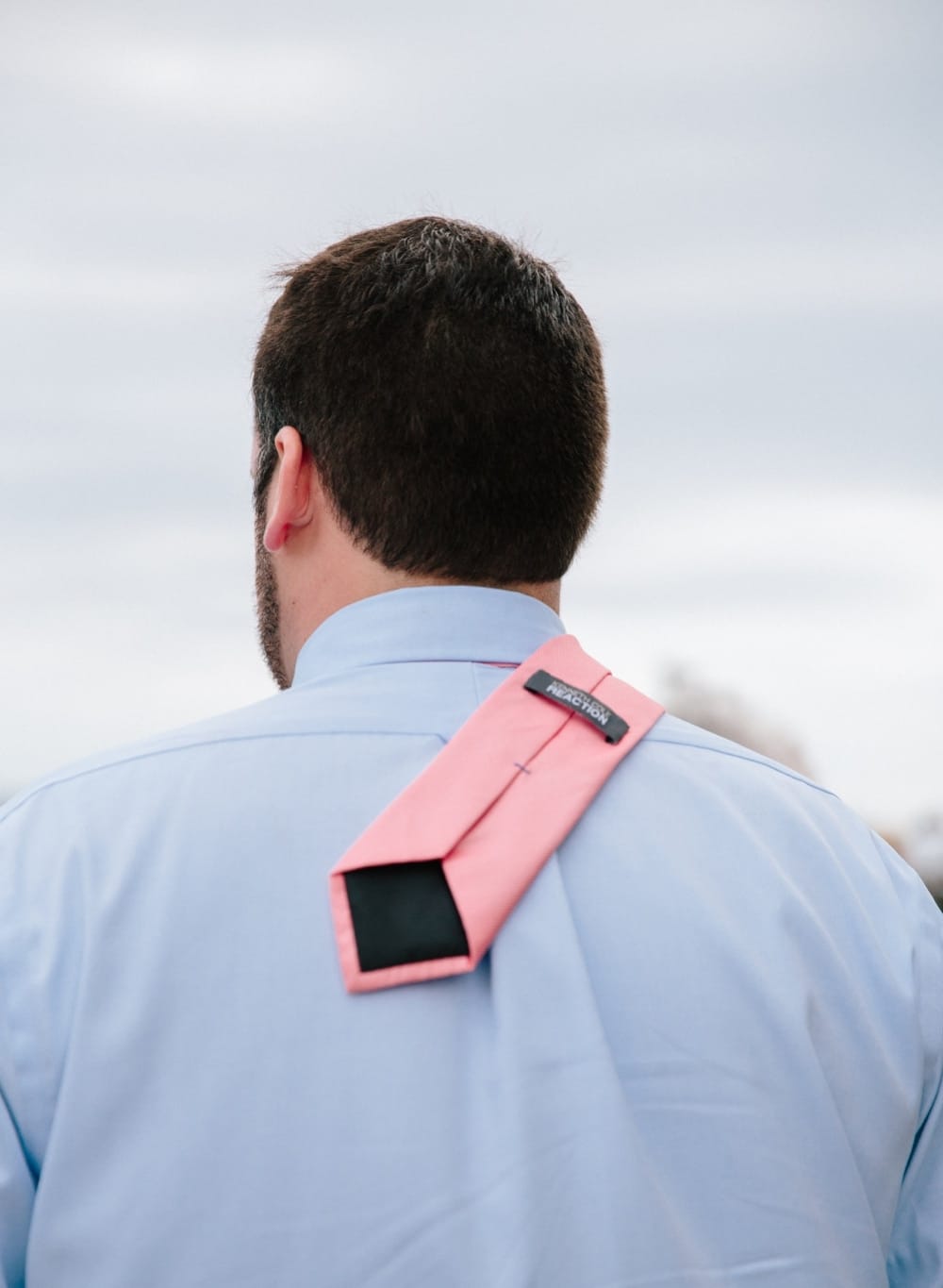 A funny photojournalistic photograph of a man's tie blowing in the wind during a outdoor wedding at Pilgrims Monument in Provincetown, Cape Cod