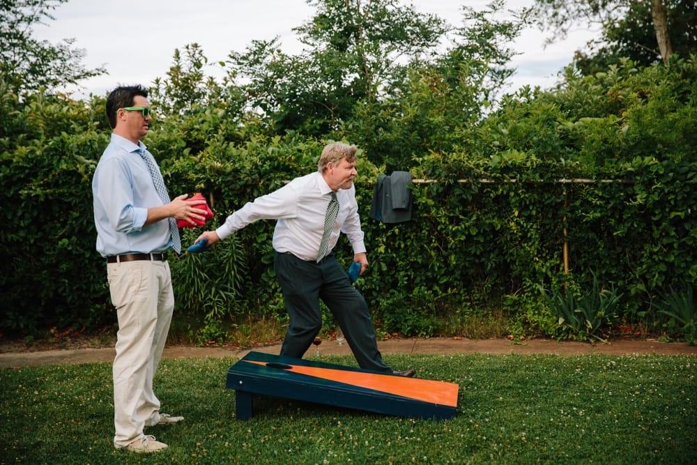 A funny photojournalistic photograph of two men playing lawn games at an outdoor wedding at Pilgrims Monument in Provincetown, Cape Cod