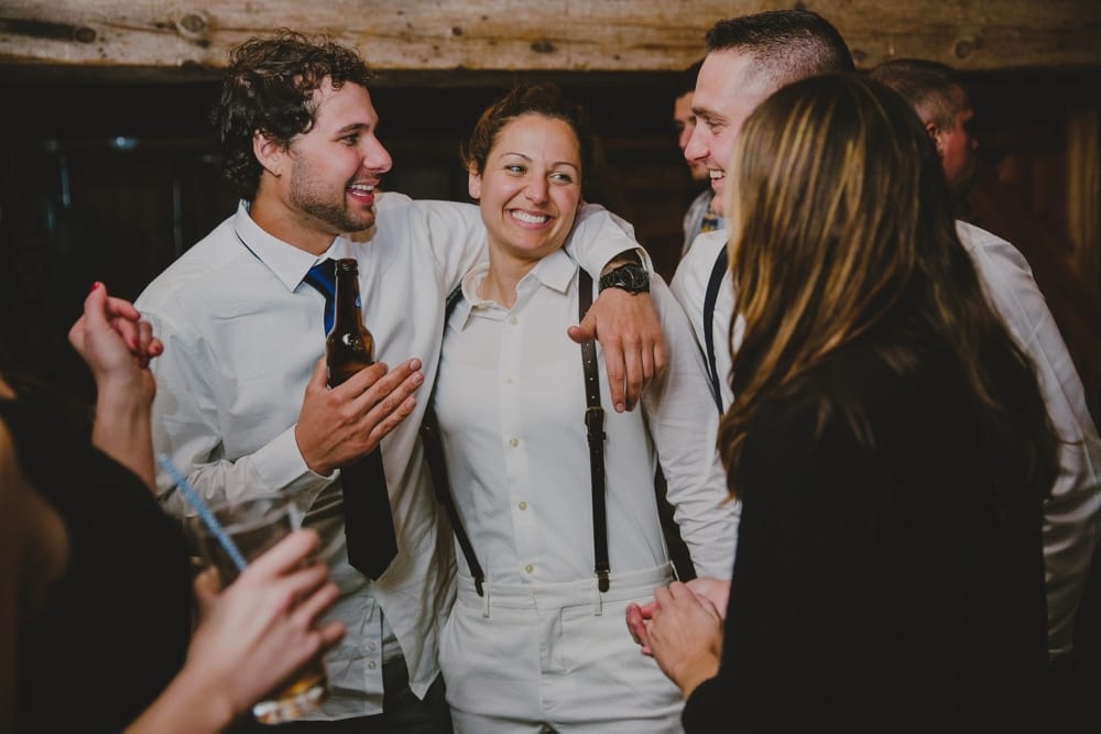 A documentary photograph of a bride talking and laughing with friends at her rustic wedding on Kitz Farm in New Hampshire