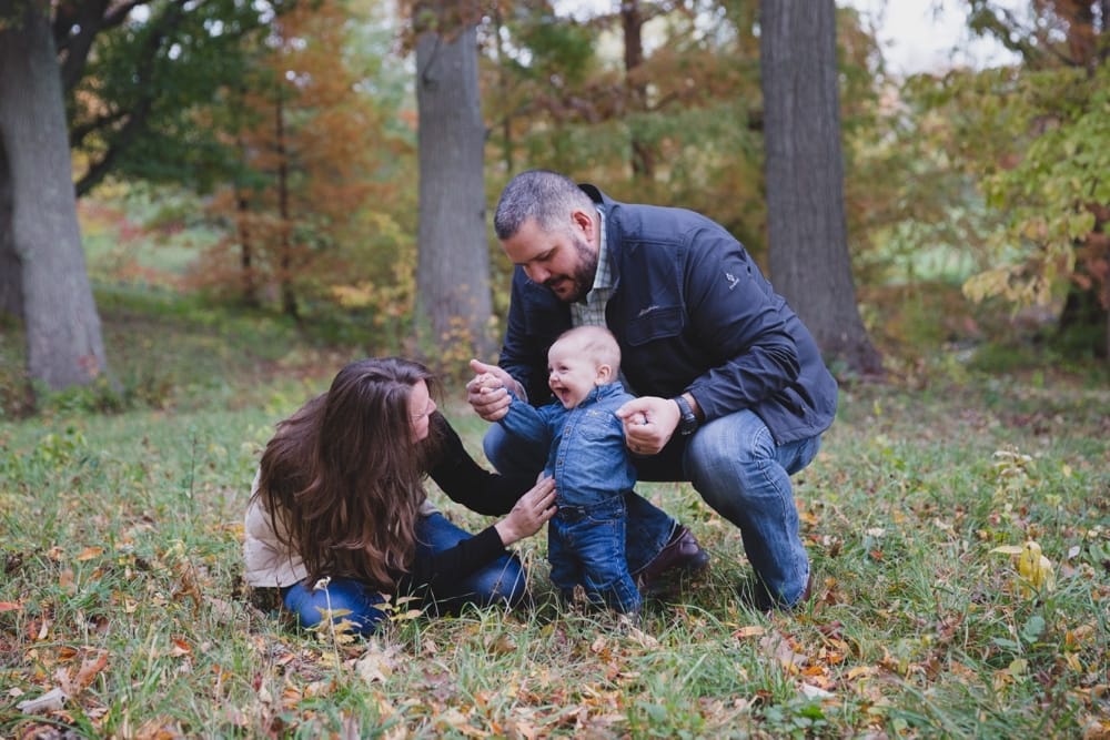 A lifestyle photograph of parents playing with their baby boy during a lifestyle mini session at the Arnold Arboretum in Boston, Massachusetts