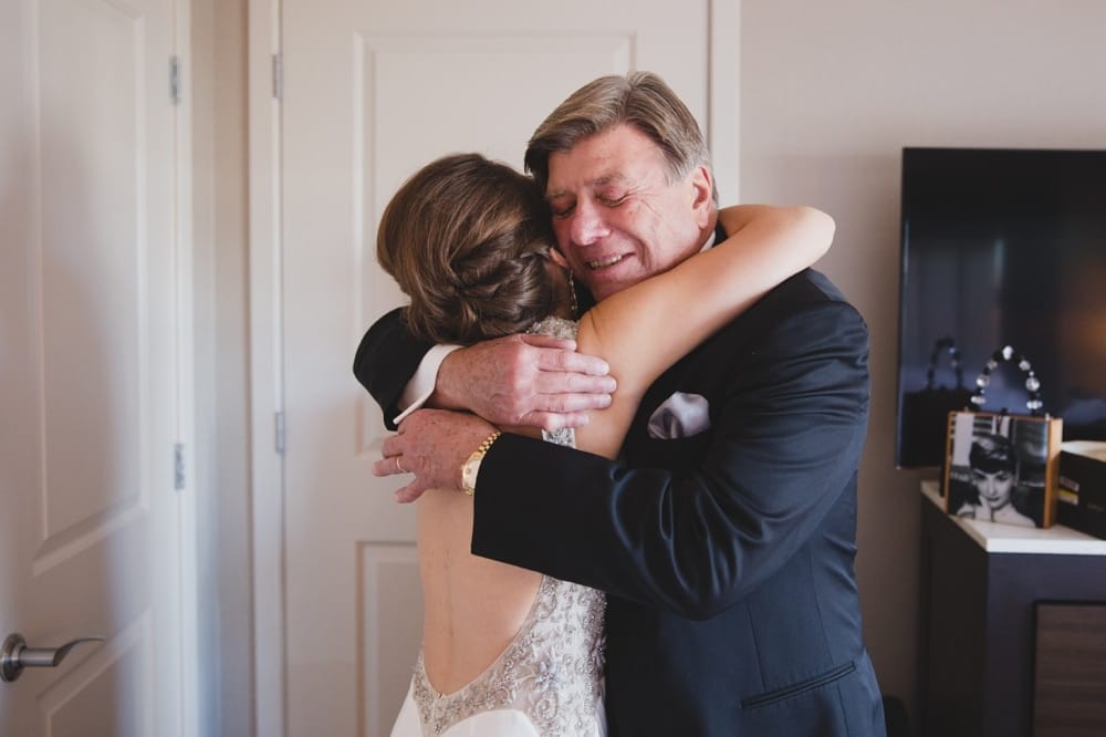 A documentary photograph of a bride hugging her father after she get dressed for her wedding at the Oceanview of Nahant in Massachusetts