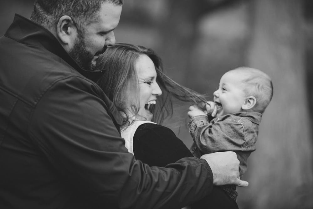 A documentary photograph of a baby boy playing with his parents during a fall lifestyle mini session at the Arnold Arboretum in Jamaica Plain, Massachusetts