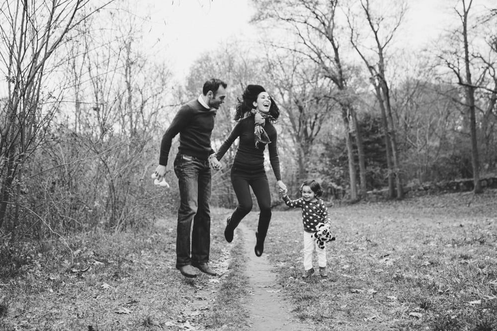 A fun lifestyle photograph of a family jumping up during their fall mini session at Boston's Arnold Arboretum in Massachusetts