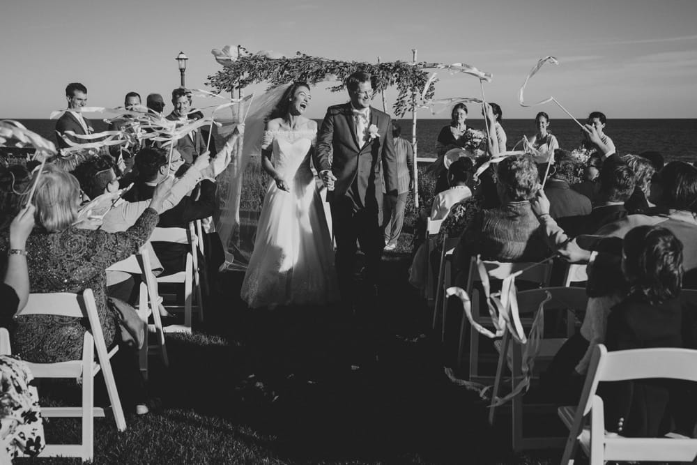 A photojournalistic photograph of bride and groom walking down the aisle after their outdoor wedding ceremony on Cape Cod