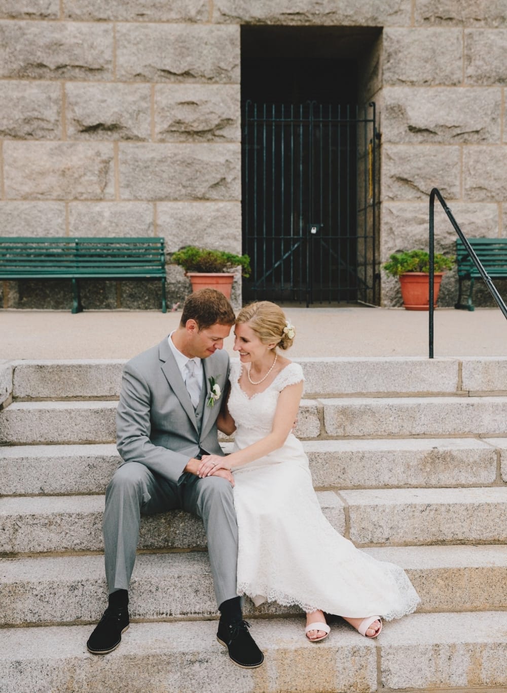 A relaxed portrait of a bride and groom sitting on the steps of Pilgrim's Monument during their fun, summer Cape Cod wedding in Provincetown, Massachusetts