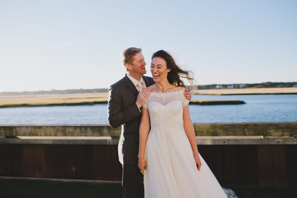 A photojournalistic photograph of bride and groom laughing after their outdoor wedding ceremony on Cape Cod