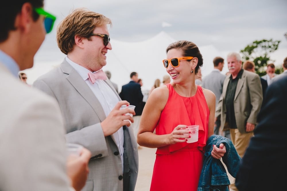 A photojournalistic photograph of wedding guest talking and laughing during a fun Cape Cod summertime wedding at Pilgrim's Monument in Provincetown, Massachusetts
