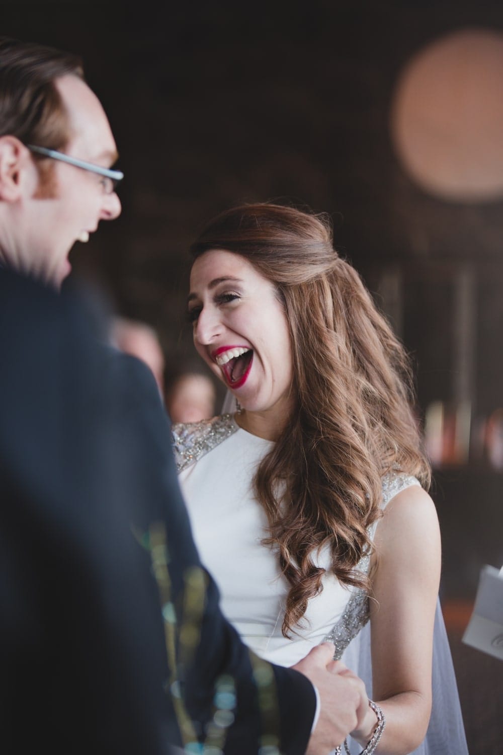 A fun photojournalistic photograph of a bride and groom smiling during their intimate and personal wedding ceremony at the Oceanview of Nahant in Massachusetts