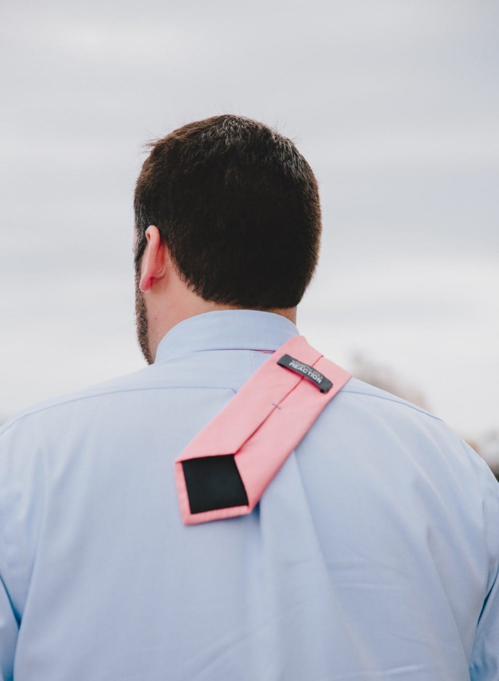 A photojournalistic photograph of wedding guest tie blowing in the wind during a fun, Cape Cod, summertime wedding at Pilgrim's Monument in Provincetown, Massachusetts