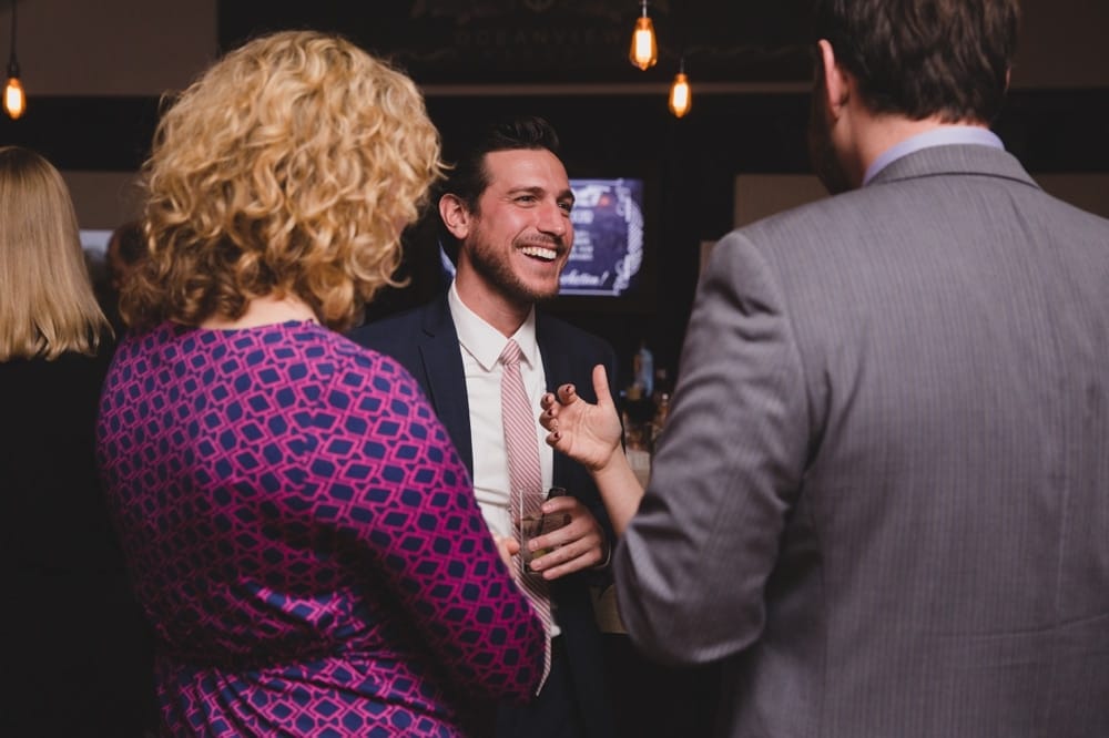 A photojournalistic photograph of wedding guests talking and laughing during cocktail hour at the Oceanview of Nahant in Massachusetts