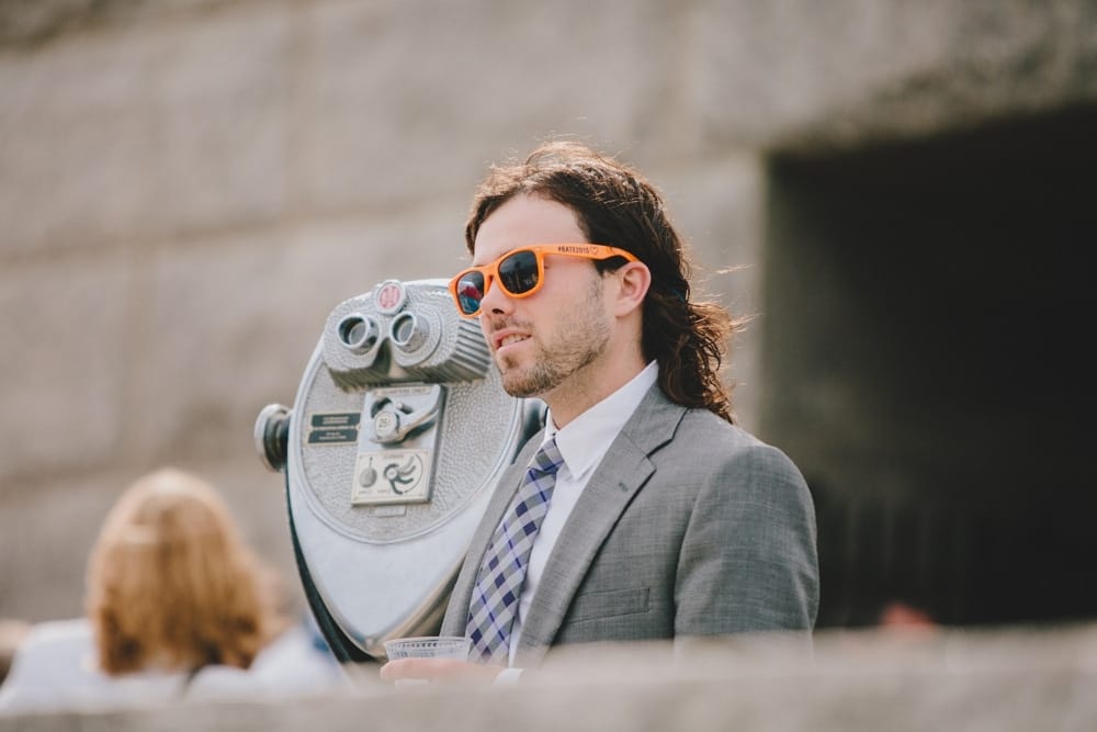 A photojournalistic photograph of a guest looking out at Cape Cod during a fun summer wedding at Pilgrim's Monument in Provincetown, Massachusetts