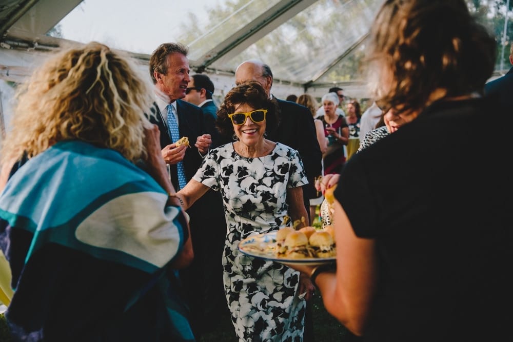 A photojournalistic photograph of wedding guest enjoying cocktail hour during a fun summertime wedding at Cape Cod's Pilgrim's Monument in Provincetown, Massachusetts