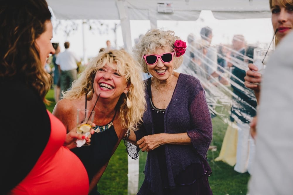 A fun documentary photograph of guests laughing during a fun cocktail hour during a summertime Cape Cod wedding at Pilgrim's Monument in Provincetown, Massachusetts