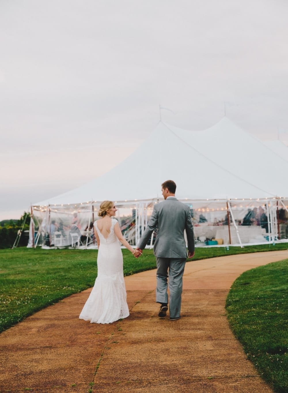 A bride and groom walk to their wedding reception at Pilgrim's Monument during a fun summer Cape Cod wedding in Provincetown, Massachusetts