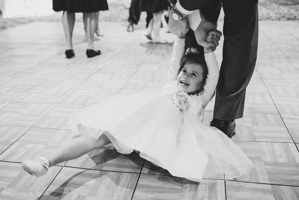 A documentary photograph of a father dancing with the flower girl at a summer time wedding in Cape Cod