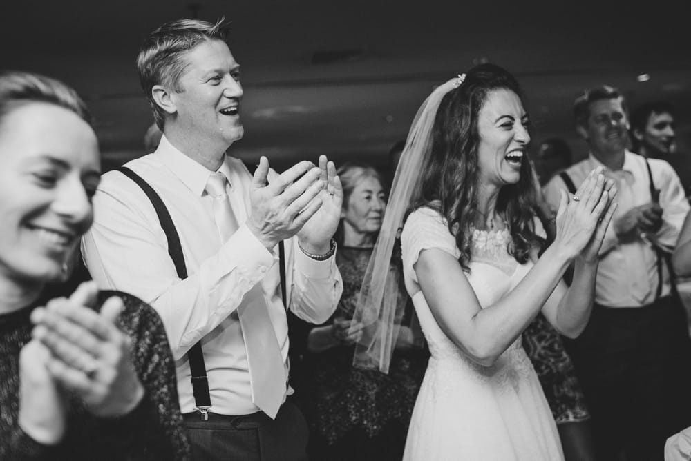 A documentary photograph of a bride and groom clapping for their guests during a summer Cape Cod Wedding