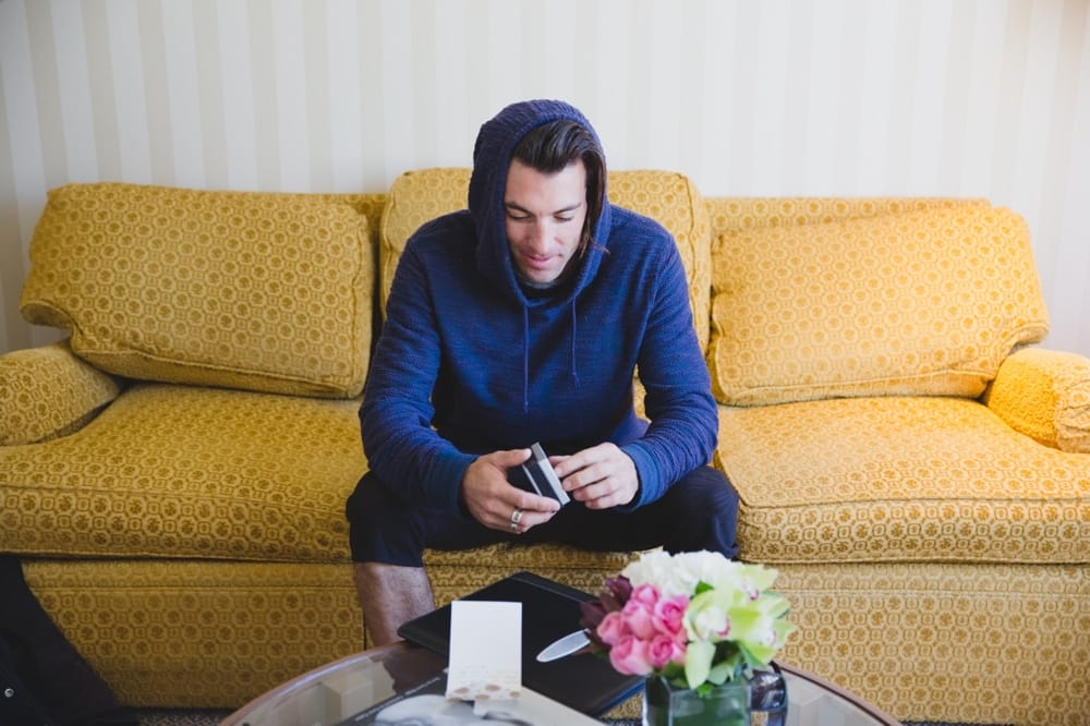 A photojournalistic photograph of the groom's friend opening his gift at the Langham Hotel before a State Room Wedding in Boston