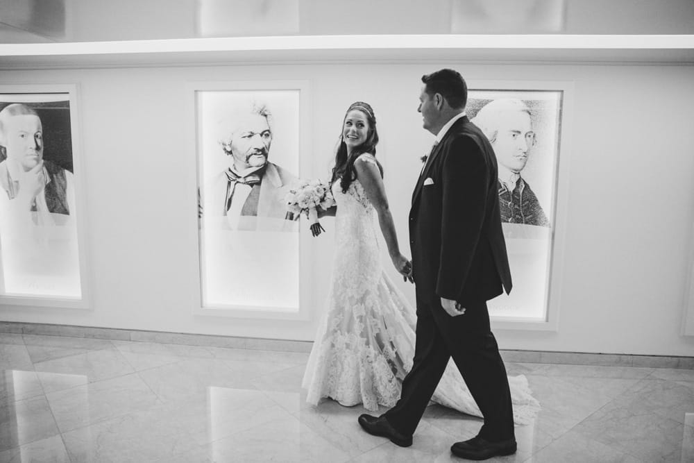 A photojournalistic photograph of a bride and groom walking through the Langham hotel before their State Room Wedding in Boston