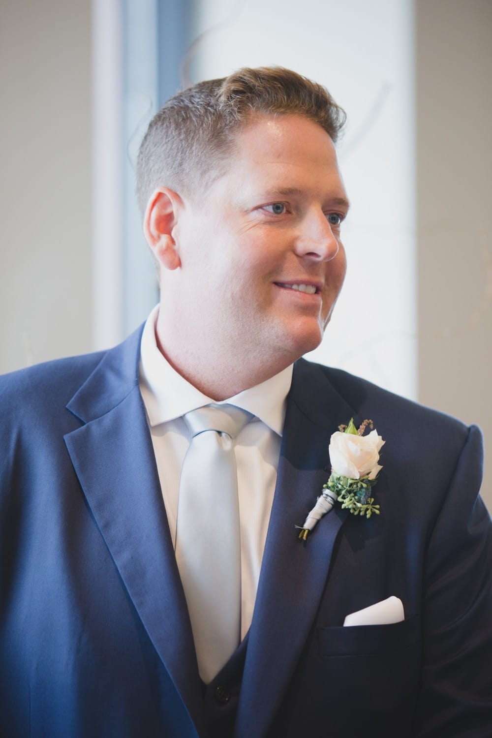 A portrait of a groom watching his bride walk down the aisle during their State Room Wedding ceremony in Boston