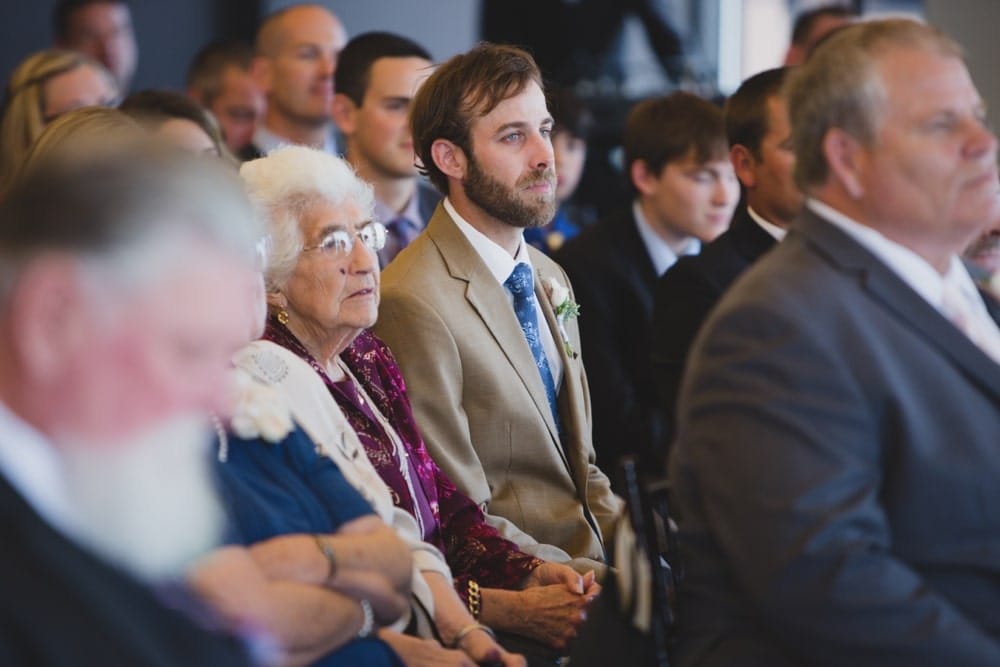 A documentary photograph of guest watching a bride and groom say their vows during their State Room Wedding ceremony in Boston
