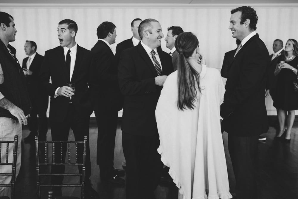 A photojournalistic photograph of guest taking and laughing during cocktail hour at a State Room Wedding in Boston