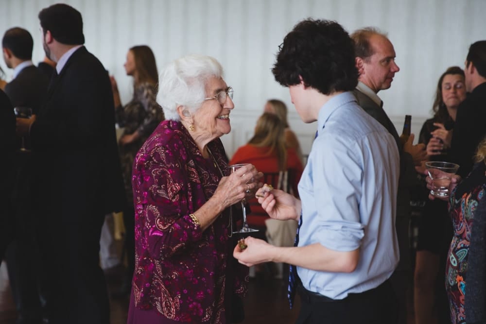 A documentary photograph of a grandmother talking to her grandchild during a State Room Wedding in Boston