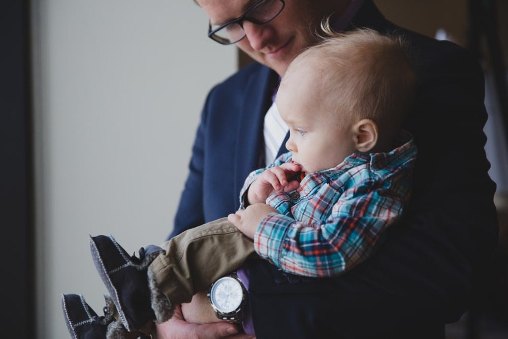 A documentary photograph of a father holding his baby boy during a State Room Wedding in Boston