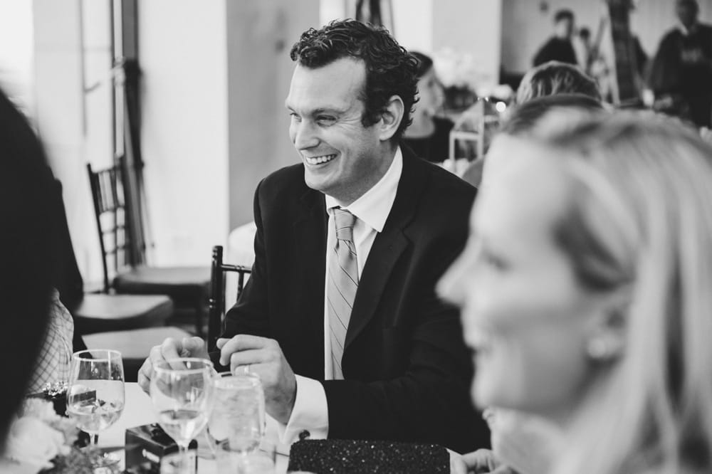 A documentary photograph of guests laughing during dinner at a State Room Wedding in Boston