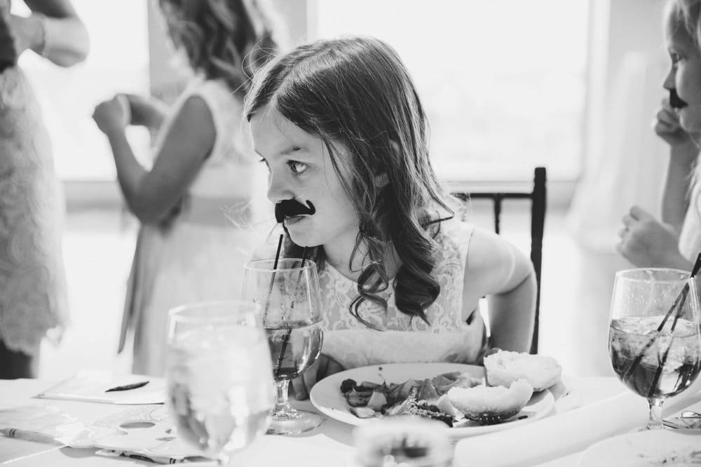 A photojournalistic photograph of a flower girl playing at the kids table during a State Room Wedding in Boston