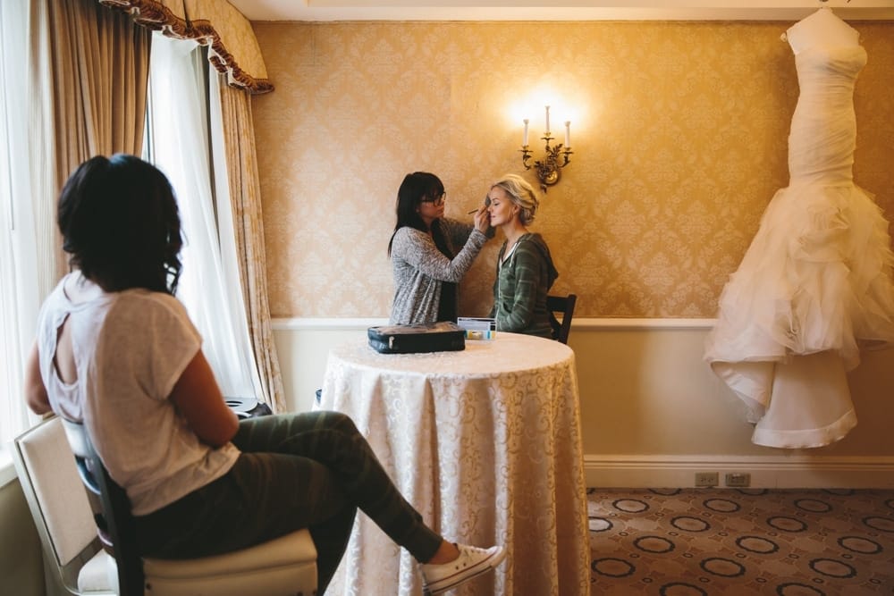 A documentary photograph of a bridesmaid watching a bride get her makeup done during a Taj Boston Hotel Wedding in the Back Bay