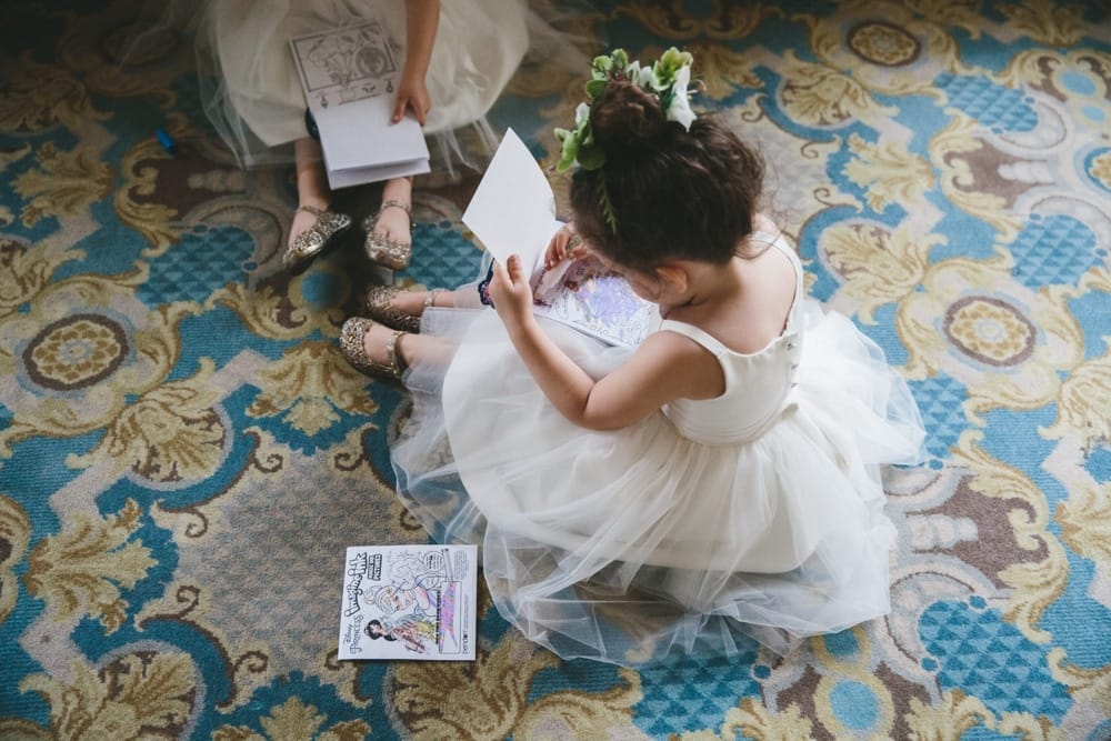 A documentary photograph of twin flower girls colouring on the floor of a hotel during a Taj Boston Hotel Wedding in Massachusetts
