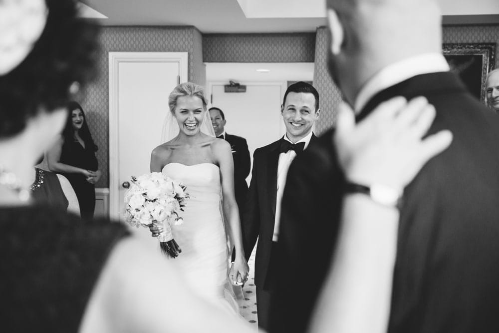 A documentary photograph of a bride and groom holding hands during the signing of ketubah at their Taj Boston Hotel Wedding