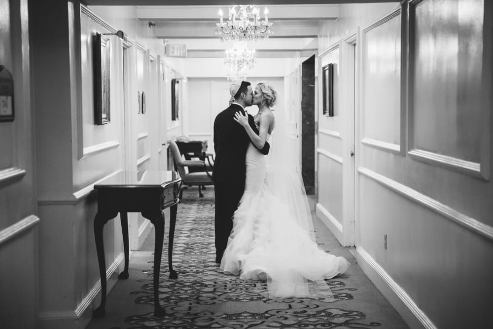 A documentary photograph of a bride and groom sharing a just married kiss as they walk through the hallway during their Taj Boston Hotel Wedding in Massachusetts