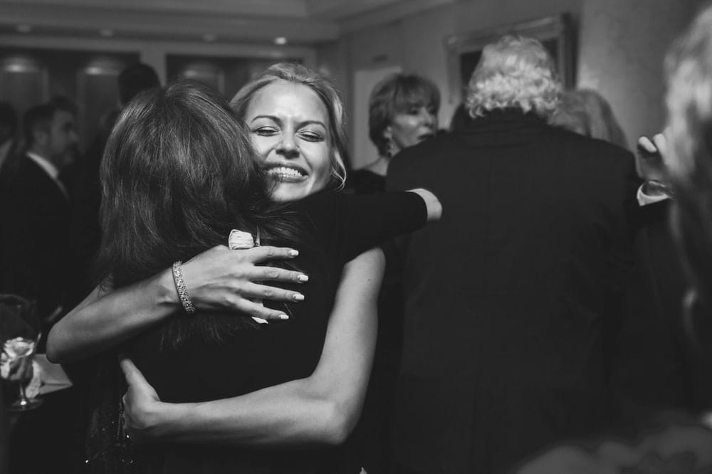 A documentary photograph of a bride hugging her friend during the cocktail hour of their Taj Boston Hotel Wedding in Massachusetts