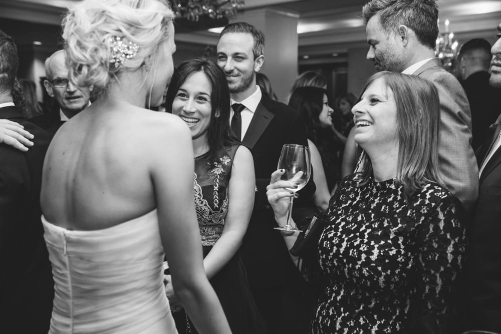 A documentary photograph of a bride laughing with friends during the cocktail hour at a Taj Boston Hotel Wedding in Massachusetts
