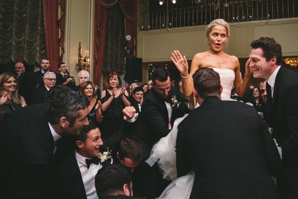 A documentary photograph of a bride sighing with relief as she is set down after the hora during their Taj Boston Hotel Wedding