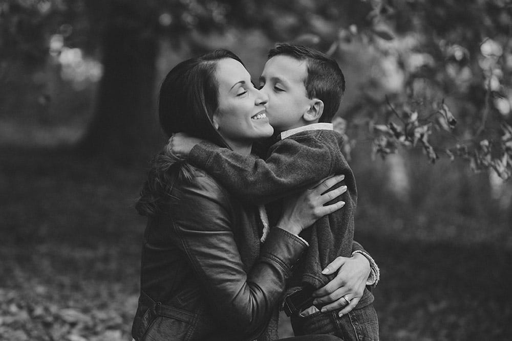 A documentary photograph depicting everyday motherhood as a son hugs his mom during a lifestyle family session at the Arnold Arboretum