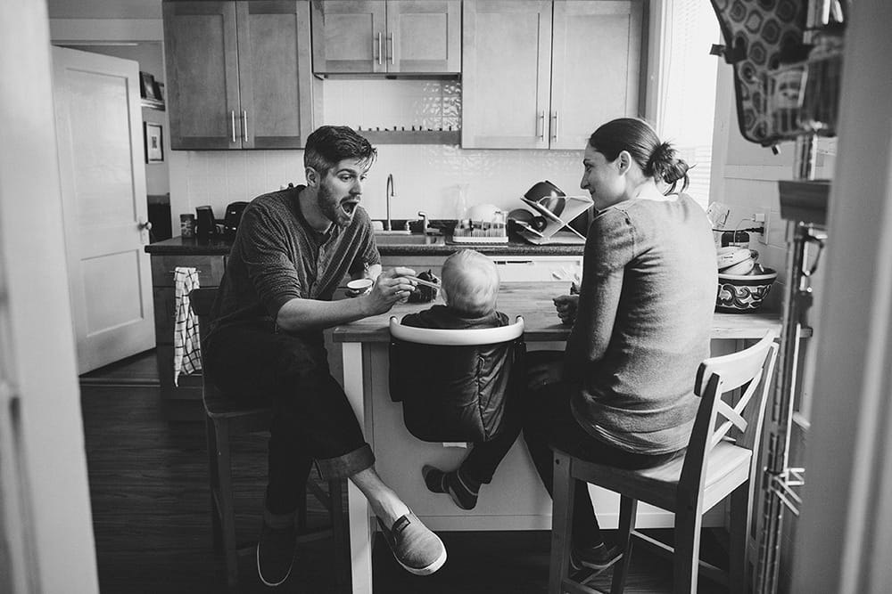 A documentary photograph of a father feeding his baby boy during a family session at home in Boston, Massachusetts