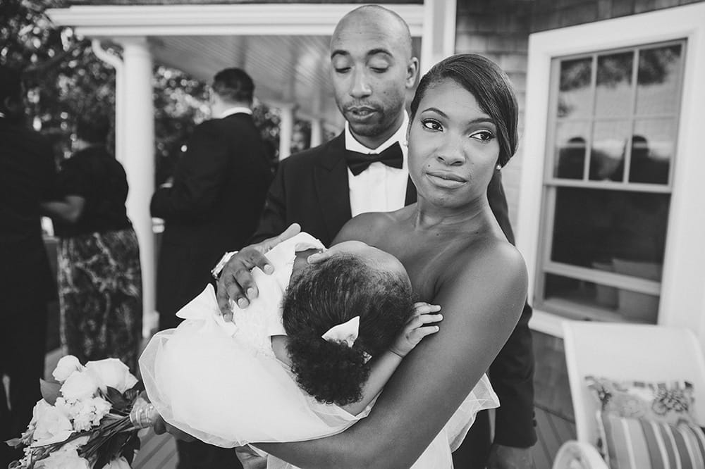 A documentary photograph of a bridesmaid holding a sleeping flower girl before a Martha's Vineyard Wedding