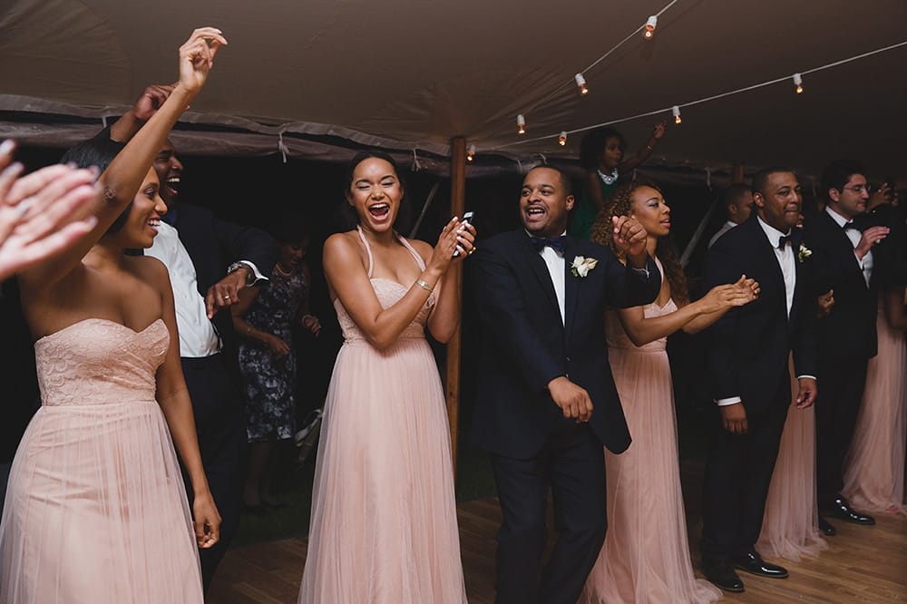 A documentary photograph of the wedding party cheering as the bride and groom enter the reception of a Martha's Vineyard Wedding