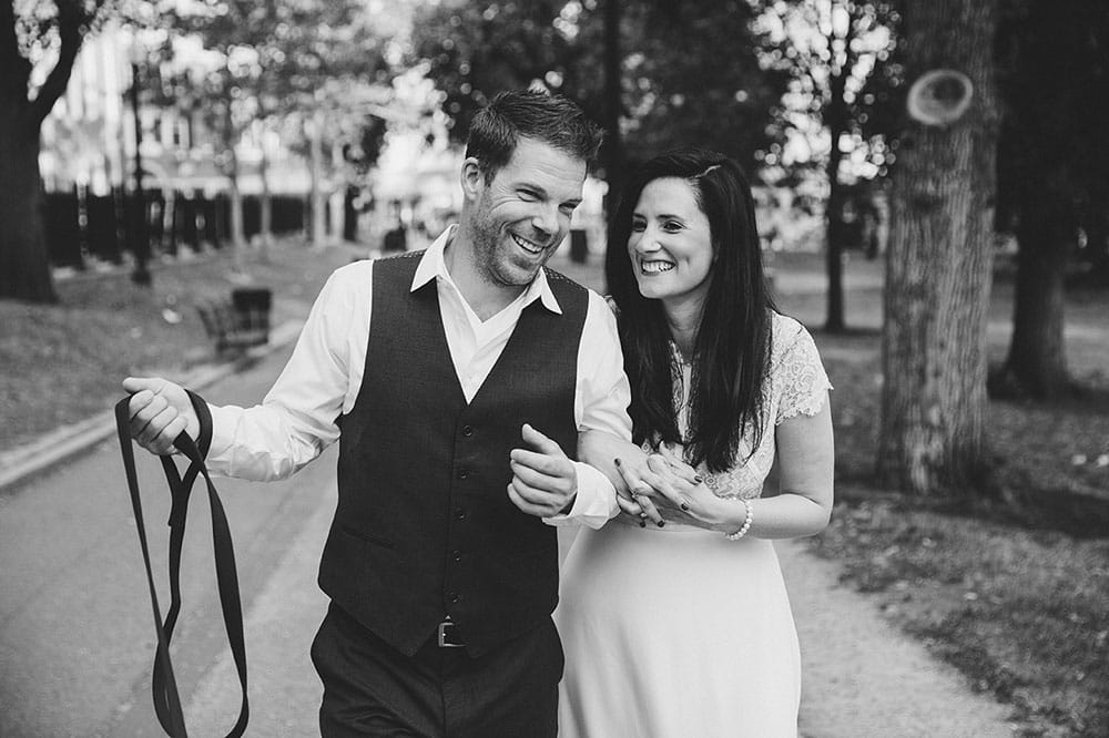 A documentary photograph of a couple walking their dog in the Boston Common during their Boston Engagement Session