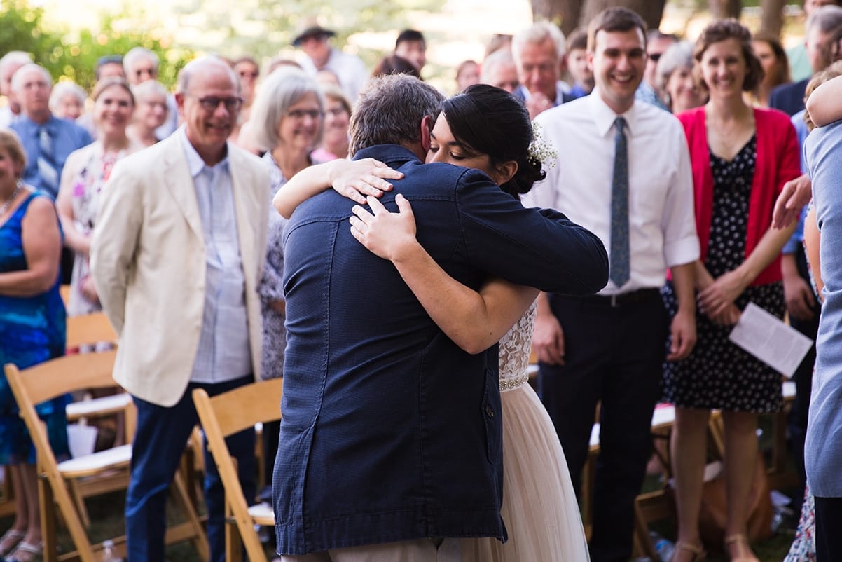 A documentary photograph of a bride hugging her father at the top of aisle during her Friendly Crossways Wedding