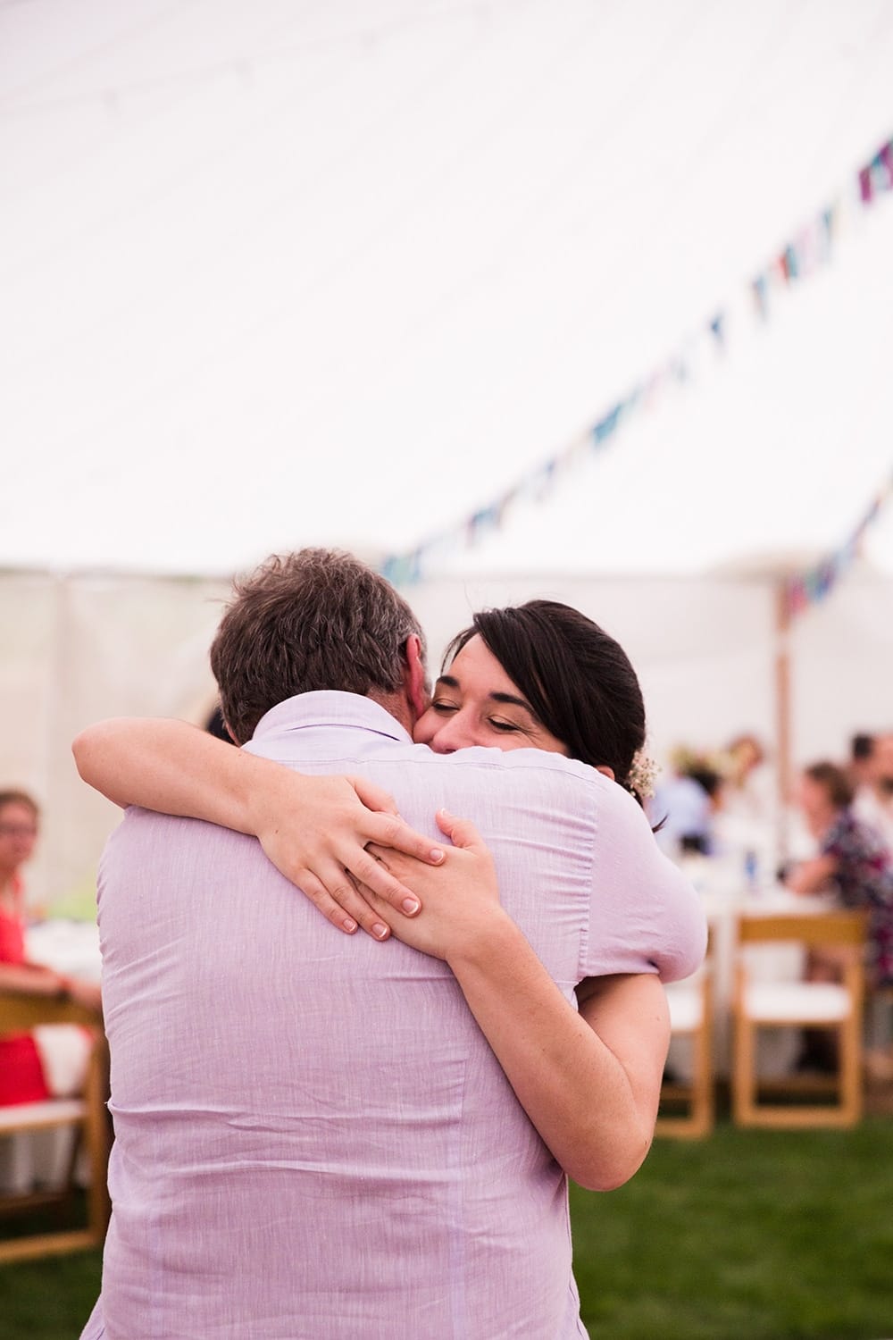 A documentary photograph of a bride hugging her father during a Friendly Crossways Wedding