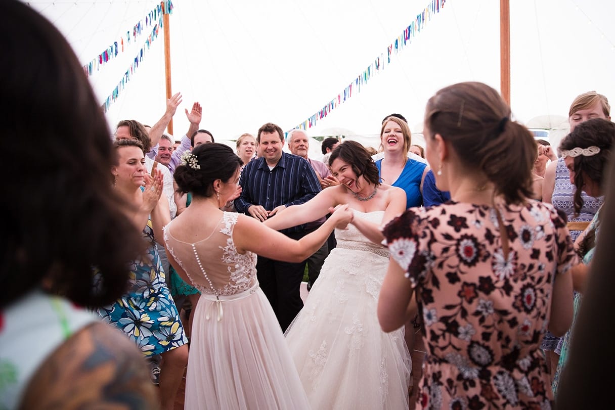 A documentary photograph of two brides dancing during their Friendly Crossways Wedding