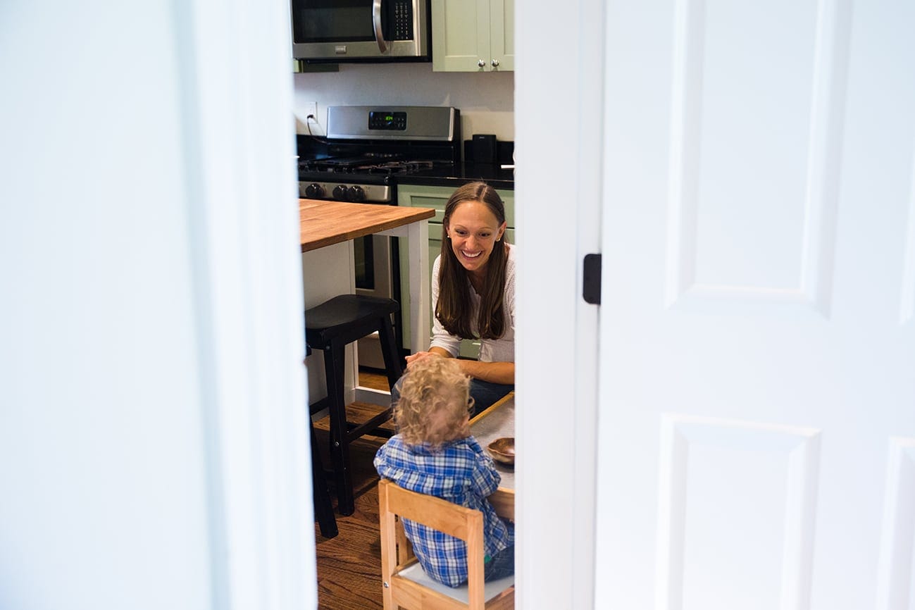 A documentary photograph of a mother sitting with her son as he has a snack during their in home family session in Boston