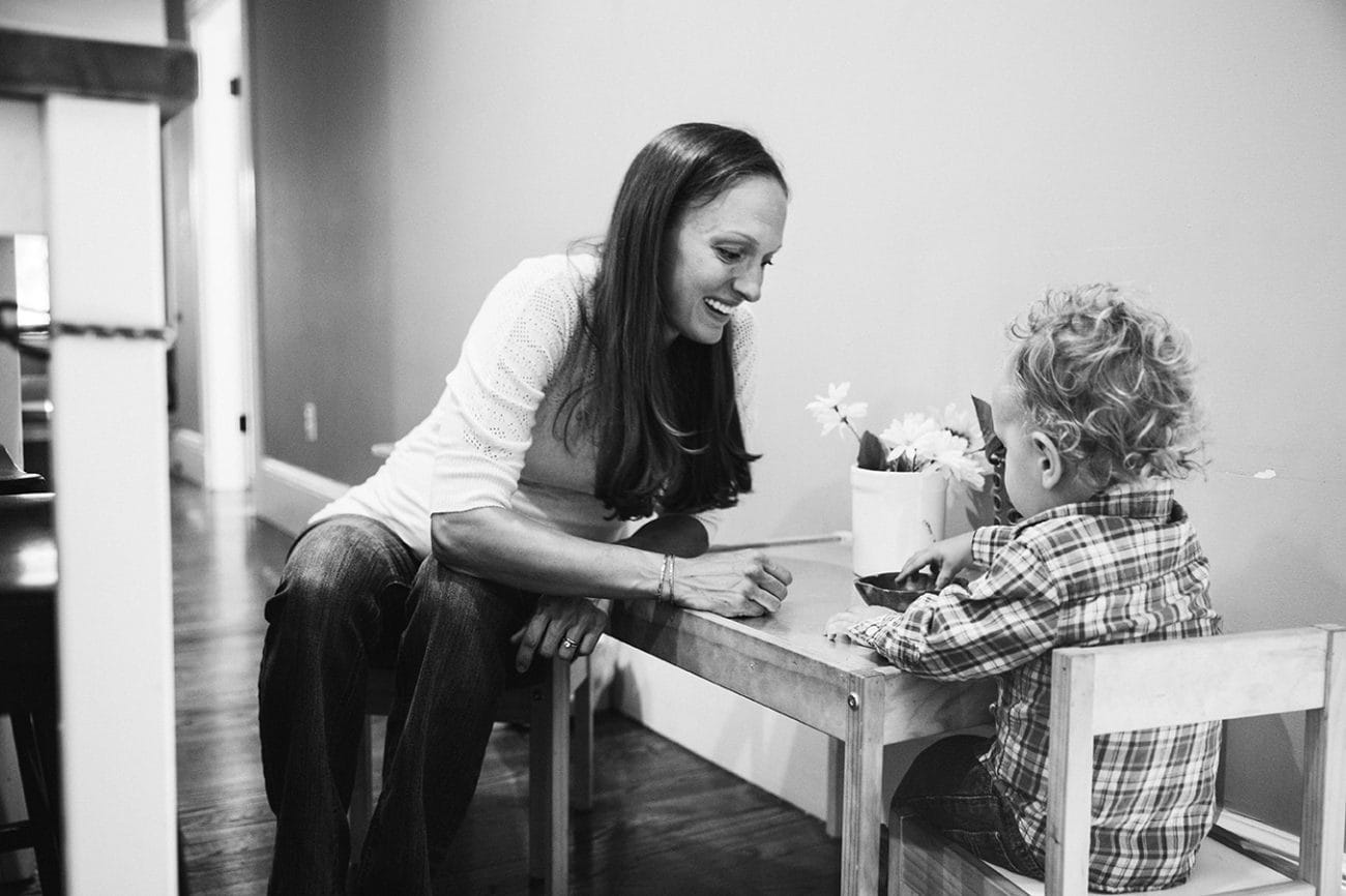 A documentary photograph of a mother and son sitting at the table and having a snack during their in home family session in Boston