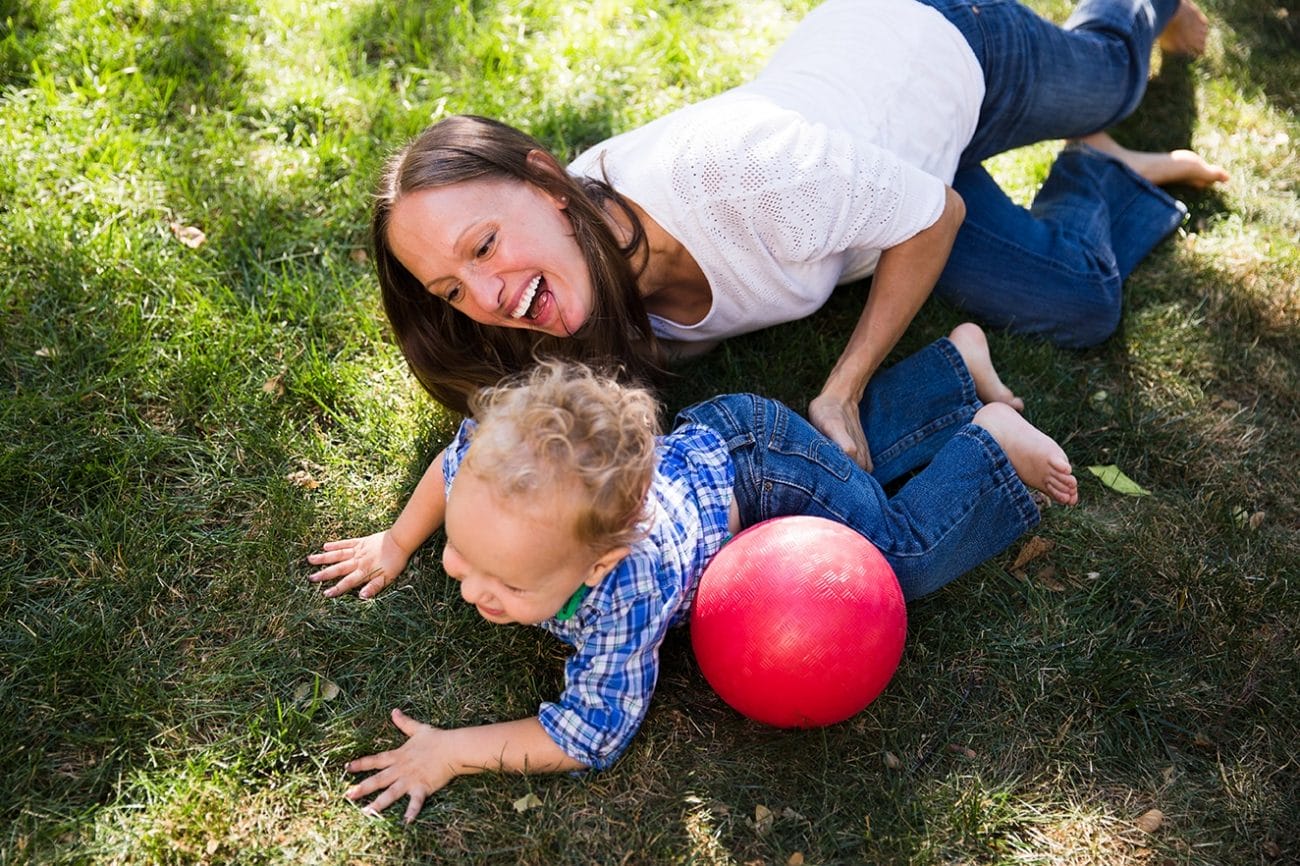 A documentary photograph of mother tickling her son during an in home family session in Boston