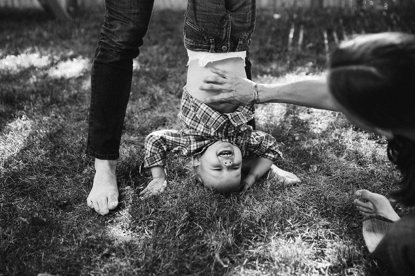 A documentary photograph of mother tickling her son during an in home family session in Boston